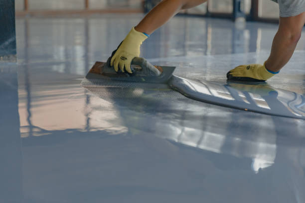 Technicien appliquant un revêtement époxy sur un sol industriel